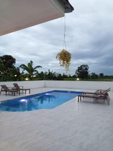 a swimming pool with two benches and a chandelier at Ranch Seda Mosegaard in Amphoe Khukhan
