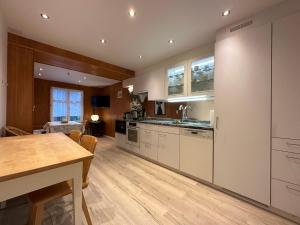 a kitchen with white cabinets and a wooden table at Chalet Surselva in Arosa