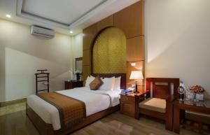 ハノイにあるVong Xua Boutique Hotelのベッド、デスク、ベッドサイドシックスが備わるホテルルームです。