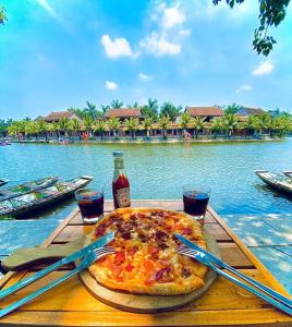 a pizza sitting on top of a table next to the water at The Banana Tree Hostel in Ninh Binh