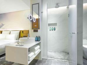 a white bathroom with a sink and a shower at Novotel Guangzhou Baiyun Airport in Huadu