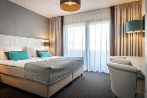 a hotel room with a bed and a window at Hotel Boschrand in De Koog