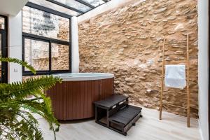 a bathroom with a tub and a stone wall at ABBI SUITES Casa Rural, Suites & Spa in Bocairent