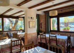 a restaurant with tables and chairs and large windows at Hotel rural Los Manzanos in Rascafría