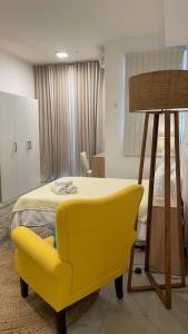 una sedia gialla e un letto in una stanza di Studio 104 Ebene Square Urban Living Apartments a Ebene