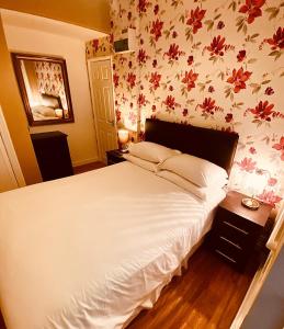 a bedroom with a white bed with floral wallpaper at Homerton House Apartments in Cambridge