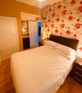 a bedroom with a white bed with flowers on the wall at Homerton House Apartments in Cambridge