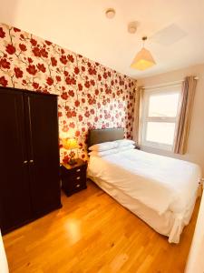 a bedroom with a white bed and floral wallpaper at Homerton House Apartments in Cambridge