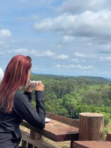 una mujer sentada en una mesa de picnic bebiendo una taza de café en Natural House Farm Stay, en Môndól Kiri