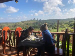 Due donne sedute a un tavolo mangiando cibo sul balcone di Natural House Farm Stay a Môndól Kiri