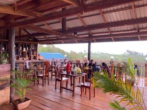 un restaurante con mesas y sillas en una terraza de madera en Natural House Farm Stay, en Môndól Kiri