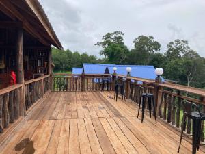 una terraza de madera con sillas y mesas en una casa en Natural House Farm Stay en Môndól Kiri