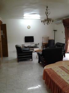 sala de estar con muebles negros y TV en Sophia Hotel, en Dar es Salaam