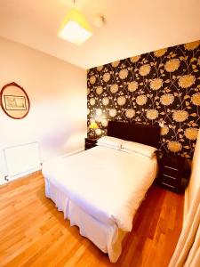 a bedroom with a white bed with a floral wallpaper at Homerton House Apartments in Cambridge