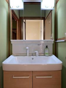 a bathroom with a white sink and a mirror at 吉田邸　古民家の落ち着いたお家 