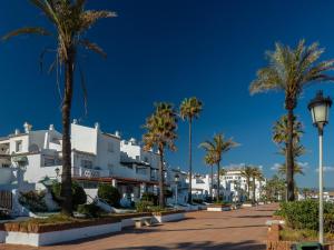 una calle con palmeras y casas blancas en 2156-Luxury apt in Cortesin golf with pool view, en Casares