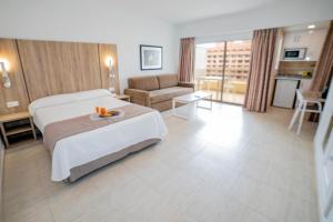 フエンヒロラにあるホテル アパルタメントス Pyr フエンヒロラのベッドとソファ付きの広いホテルルームです。