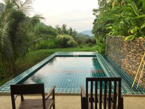 einen Pool mit 2 Stühlen und einem Tisch in der Unterkunft Patong Garden House - Luxury Villa in Patong Hills in Patong Beach