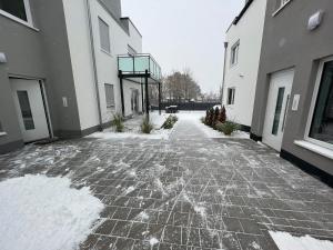 a stone walkway with snow on the ground between two buildings at ApartHotel Roxheim in Roxheim