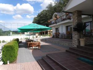 eine Terrasse mit einem Tisch und einem grünen Sonnenschirm in der Unterkunft Mery Ján in Podhájska