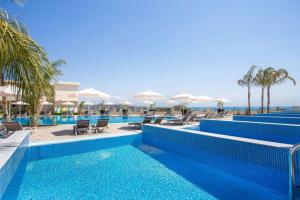 - une piscine avec des chaises longues et des parasols dans un complexe dans l'établissement Venezia Resort Hotel, à Faliraki