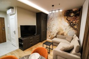 - un salon avec un canapé et une télévision dans l'établissement D Apartments Centrum Ziemia, à Białystok