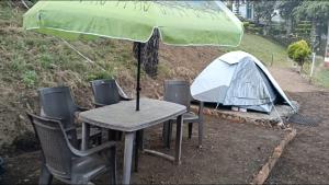 a tent and a picnic table with a green umbrella at Nainital Adventure Park & Resort in Nainital