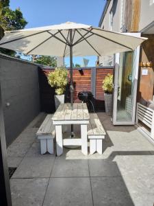 a white picnic table with an umbrella on a patio at Cottages20 in Coffee Bay