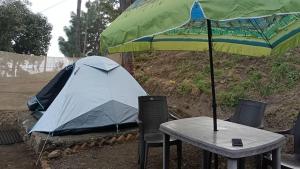 a tent and a table and chairs with a table and umbrella at Nainital Adventure Park & Resort in Nainital