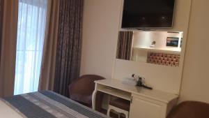 a hotel room with a bed and a desk and a television at Hotel Holiday Maria in Băile Herculane