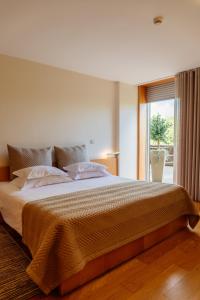 ein Schlafzimmer mit einem großen Bett und einem Fenster in der Unterkunft Axis Ponte de Lima Golf Resort Hotel in Ponte de Lima