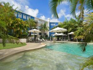 una piscina frente a un hotel con árboles y sombrillas en Unit 41 at Portobello Dicky Beach en Caloundra