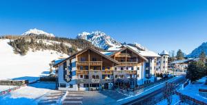 a hotel in the snow with mountains in the background at Apart Residence Rautal ***S in San Vigilio Di Marebbe