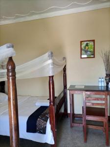 a bedroom with a canopy bed and a desk at Pross Residence in Masindi