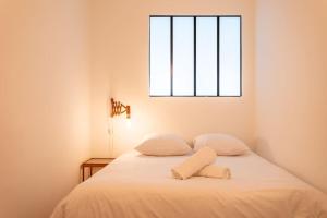 a bedroom with a bed with white sheets and a window at Vieux Port : Le Pavillon in Marseille