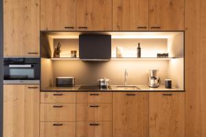 cocina con armarios de madera, fregadero y fogones en All-Suite Resort Paznaun en Galtür