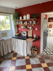 a kitchen with a counter and a red wall at La Chaise Haute in Hagetmau +20 photos