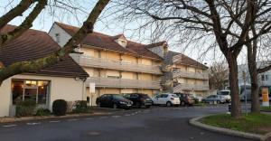 un bâtiment avec des voitures garées dans un parking dans l'établissement Campanile Villepinte - Parc des Expositions, à Villepinte