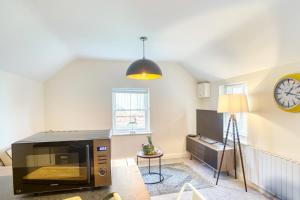 a living room with a microwave and a clock on the wall at Pass the Keys Cosy flat in the Town Centre in Sleaford