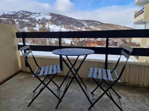 einen Tisch und zwei Stühle auf einem Balkon mit Aussicht in der Unterkunft Boost Your Immo Risoul Le Diamant 823 in Risoul