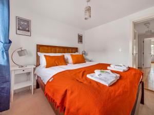 een slaapkamer met een groot bed met oranje lakens en handdoeken bij Pass the Keys Stylish 2BR Apartment Parking x 2 Oxford in Oxford