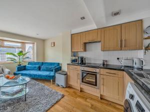uma cozinha com armários de madeira e um sofá azul em Pass the Keys Stylish 2BR Apartment Parking x 2 Oxford em Oxford