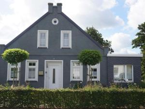 uma casa cinzenta com duas árvores em frente em FeWo Nordseeflair OG - Wiarden em Wiarden