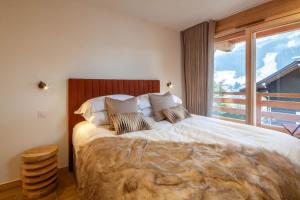 a bedroom with a large bed with a large window at Chalet Tilly in Morzine