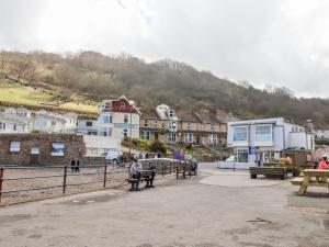 a person sitting on a bench in front of a town at Beach Road House in Ilfracombe