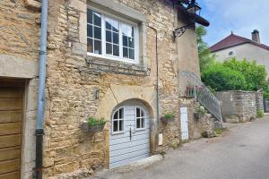 a stone building with a door and a window at Le petit cocon de Chateau Chalon in Château-Chalon