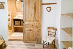 a bathroom with a wooden door and a chair at Le petit cocon de Chateau Chalon in Château-Chalon
