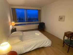 a bedroom with a white bed and a window at Tour Défense 2000 Magnifique Appartement in Puteaux