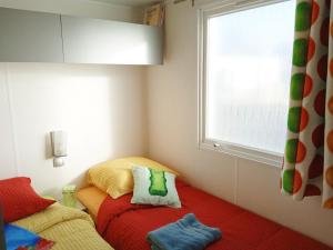 a small bedroom with a bed and a window at Mobil home-Les Lins Bleus in Biville-sur-Mer