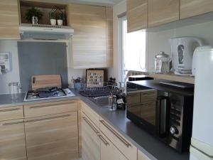 a kitchen with wooden cabinets and a stove top oven at Mobil home-Les Lins Bleus in Biville-sur-Mer